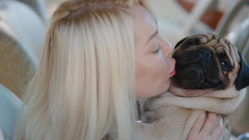 Woman Kisses her Beloved Pug Puppy