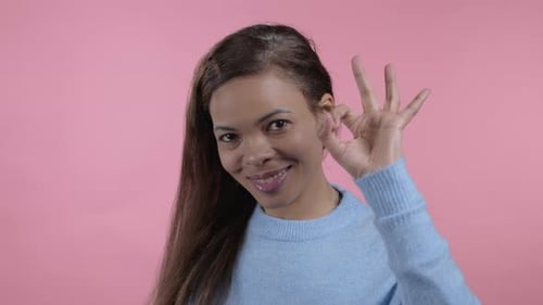 Afrikanerin zeigt Ok-Zeichen über rosa Studio-Hintergrund
