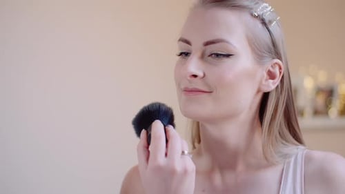 Woman Applying Makeup with a Brush Indoors