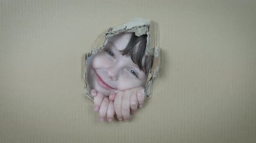 Smiling Child Pokes Through Cardboard Box Hole
