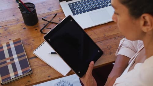 Young Adult Using Tablet at Wooden Desk