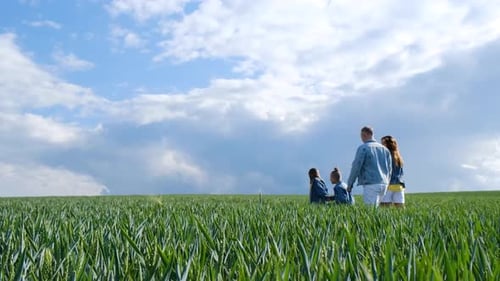 Family Walking Together Through Green Field on Sunny Day