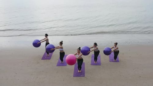 Aerial view of group of Asian women in yoga class club doing exercise and yoga at natural beach