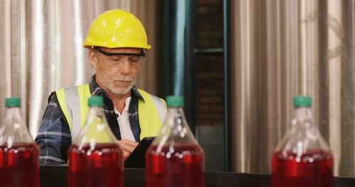 Worker using digital tablet in bottle factory