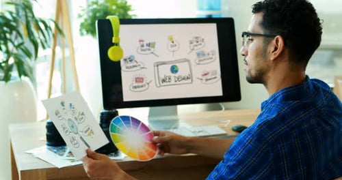 Man compares web design sketches with color wheel