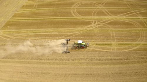 Tractor plows ground on cultivated farm field.