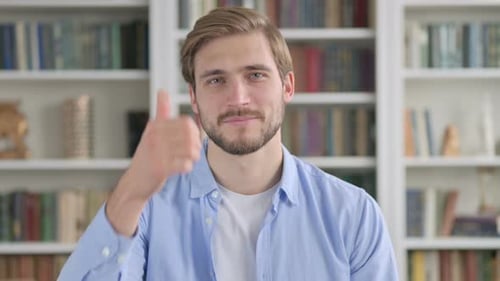 Man Gives Thumbs Up in Front of Bookshelf