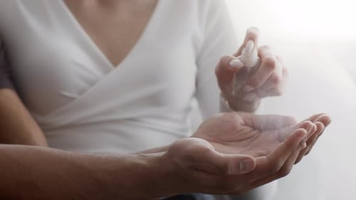Couple Sanitizing Hands Indoors in Daylight