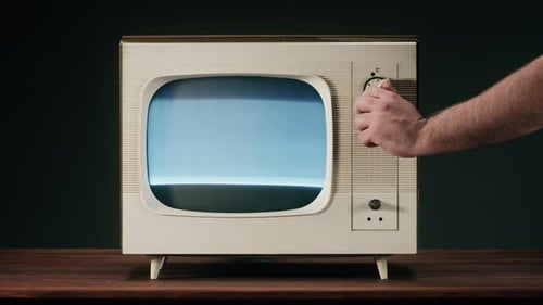 Hand Adjusts Dial on Retro Television Set