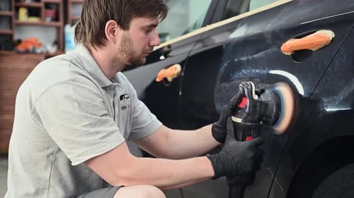 Man Polishing Car in Garage Using Power Buffer