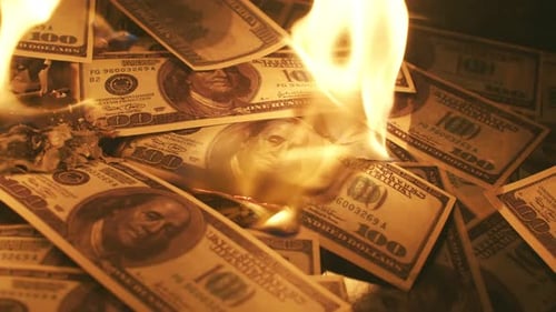 Bunch of dollar bills slowly burn up in closeup Macro. Concept of a big waste of money