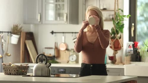 Woman Sipping Coffee in Bright Kitchen at Home