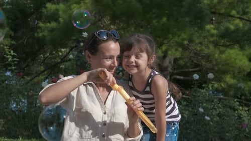 Woman and Child Blowing Bubbles Outdoors