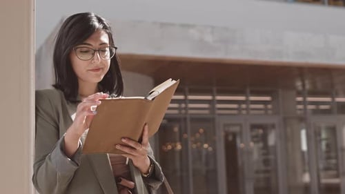 Young Woman Reading Book in the City
