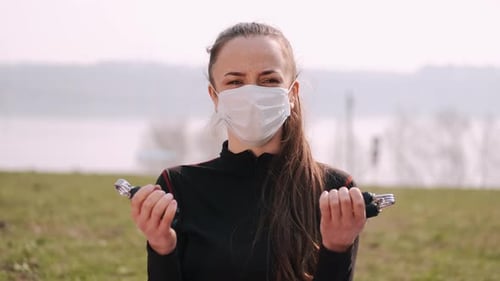 Une femme athlétique portant un masque de protection fait de l'exercice avec des poignées
