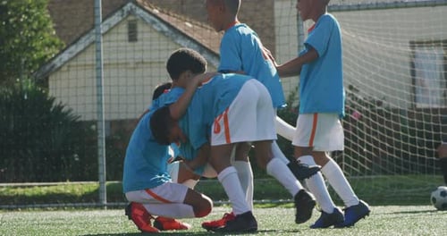 Soccer kids in blue smiling and cheering up in a sunny day
