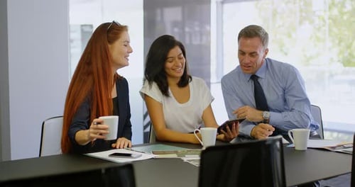 Team Discussing Business Using Tablet in Boardroom