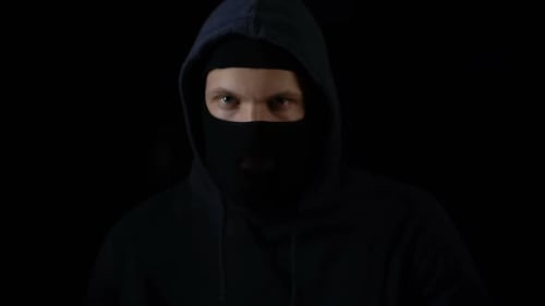 Man in Balaclava Shining Flashlight Towards Camera