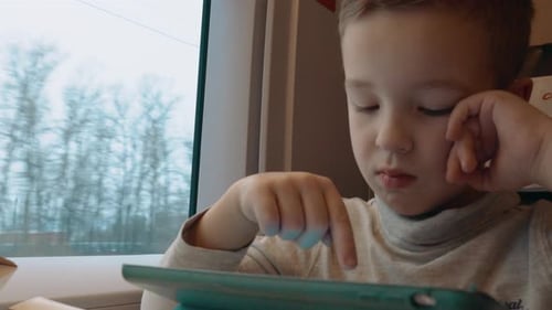 Child Using Tablet Device on a Train