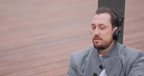 Close Up of Young Man's Face with Mustaches and a Beard Who Sits on the Wooden Floor in the Square