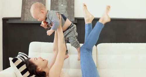 Happy Mother Playing With Infant on Couch