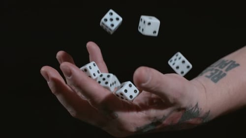 Hand Drops Dice on Reflective Black Surface