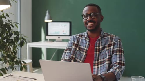 Portrait of Smiling Afro-American Man Sitting at Desk in Office