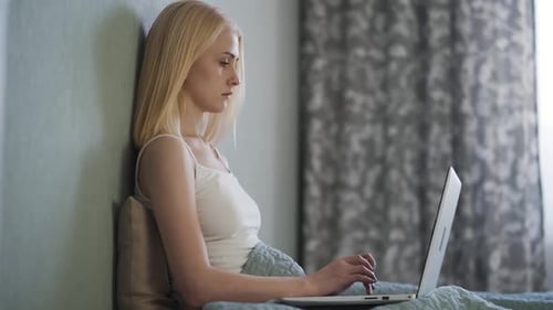 Woman Typing on Laptop While Sitting in Bed