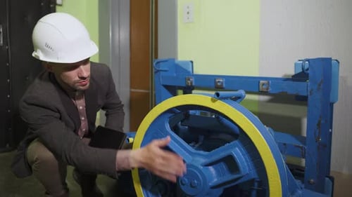 Un technicien en casque vérifie la qualité d'assemblage du nouvel entraînement électrique d'ascenseur