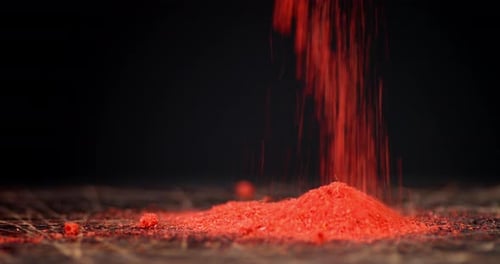 Vibrant Red Powder Falling onto Dark Surface
