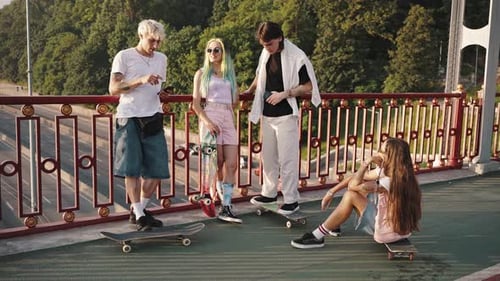 Friends with Skateboards Hanging Out on a City Bridge