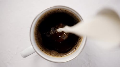 Milk Poured into Coffee in White Mug