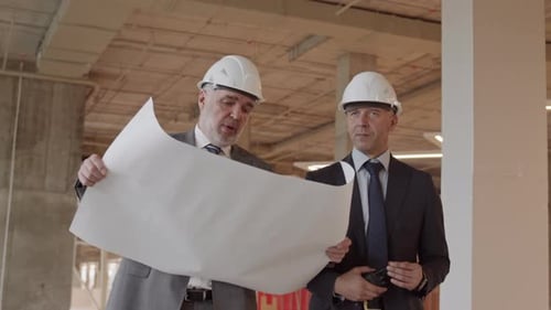 Engineers Review Blueprints in Construction Site