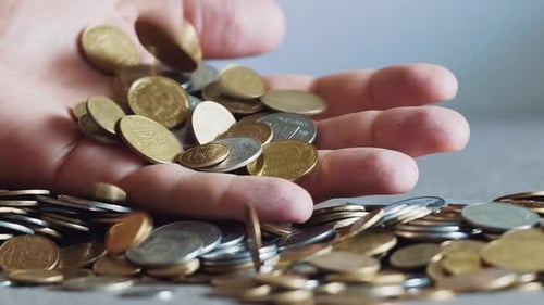 Hand Holding and Dropping Shiny Gold Coins