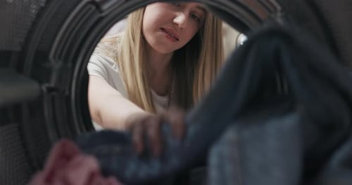 A Woman is Doing Laundry the View From Inside the Washing Machine Puts Colored Clothes in to Be Spun