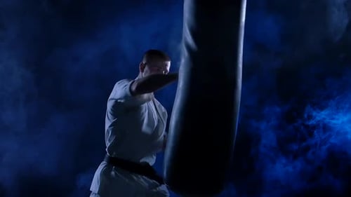 Man Practicing Karate with Punching Bag in Dark