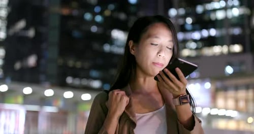 Woman Uses Smartphone in City at Night