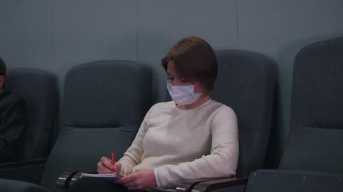 Woman Writing in Notebook Wearing a Face Mask