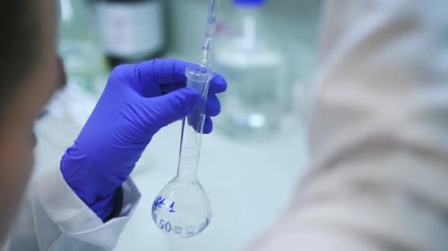 Scientist Adds Fluid to Flask in Lab Close Up