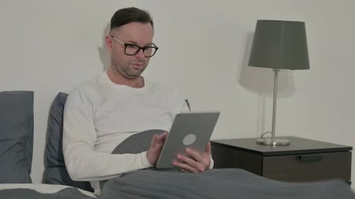 Man Using Tablet While Relaxing in Bed