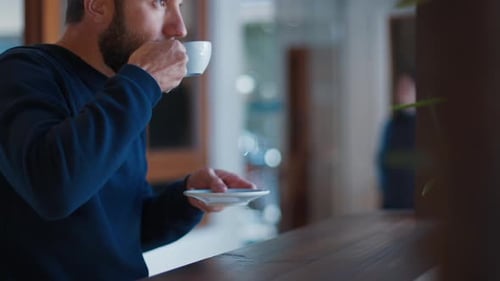 Relaxed Caucasian Man with Beard Drinks Coffee in a Cafe