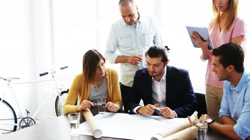 Team Discussing Architectural Plans in Bright Office