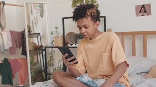 Teen on Bed Looking at Phone Indoors