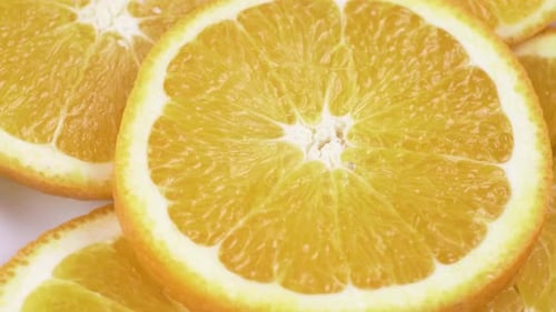 Close up fresh valencia orange sliced with white background shallow focus and slowly rotating.
