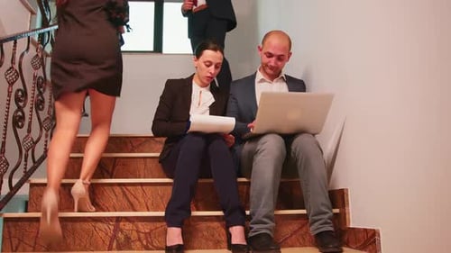 Business People Analysing Reports Sitting on Stairs