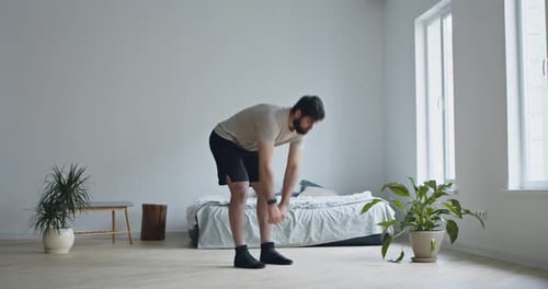Man Stretching in Bedroom During Day