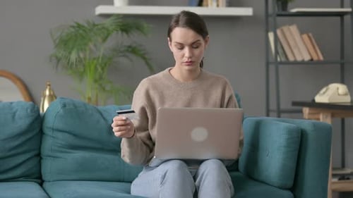 Woman Making Online Payment on Laptop on Sofa