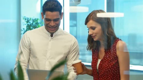 Colleagues Work Together in Modern Office with Laptop