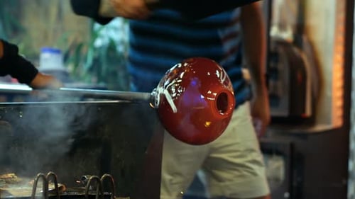 Glass Blower Shaping Molten Glass in Workshop