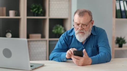 Senior Man Using Smartphone at Desk